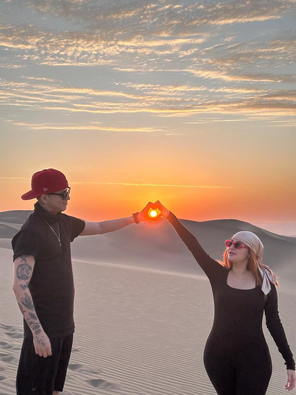 Pareja formando un corazón con el sol